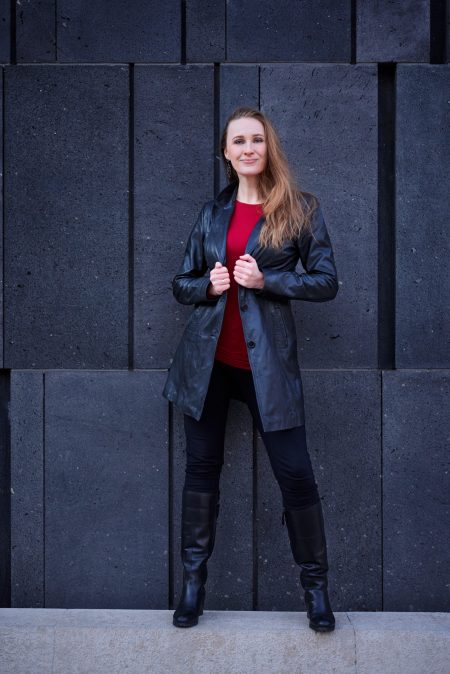 Body language, voice and mindset trainer Christiane Reiseder in front of a black wall